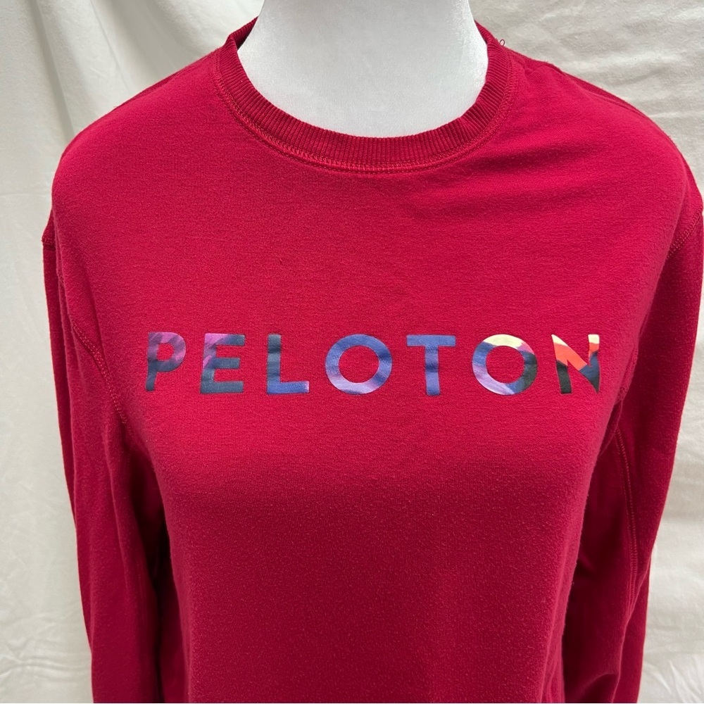 Peloton cranberry colored lightweight sweatshirt with multi-color brand name.